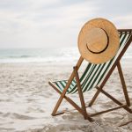 Straw hat kept on empty beach chair